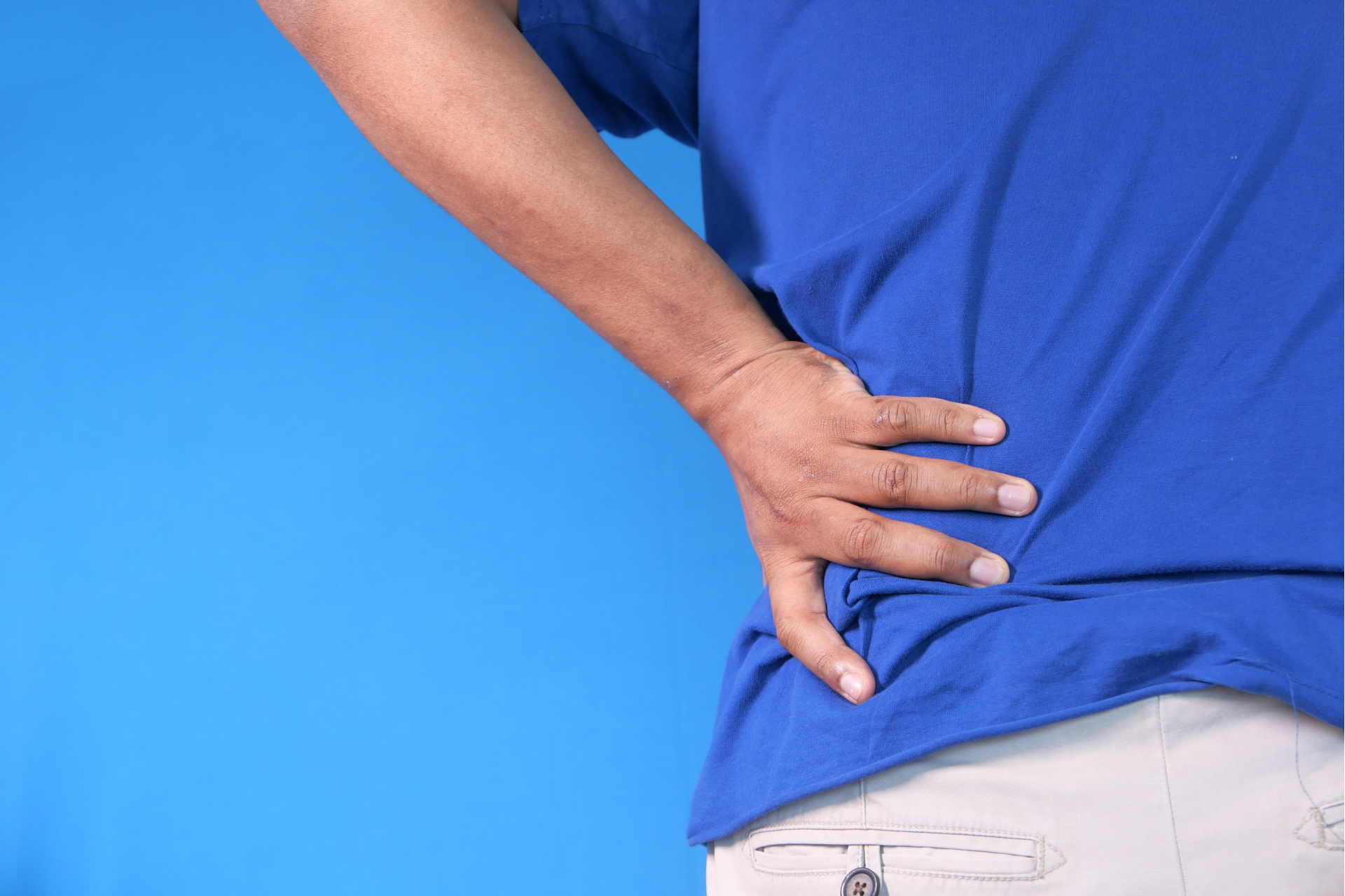 Person using their hand to try and ease their lower back pain